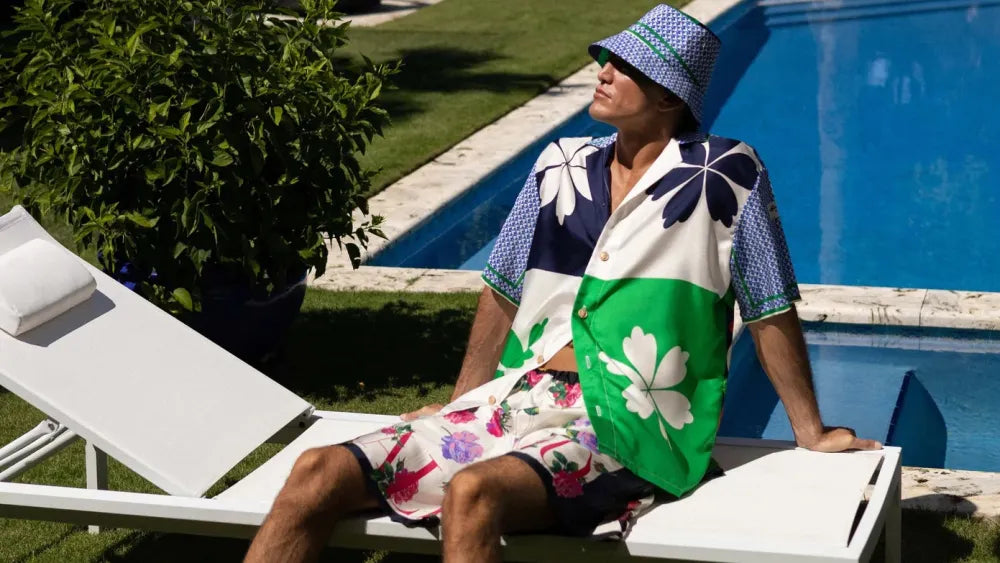 A male model wears a style from J. Logan Home beside a pool