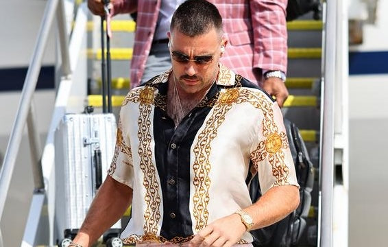 Travis Kelce leaving a plane in a black and gold chain-print J. Logan Home shirt