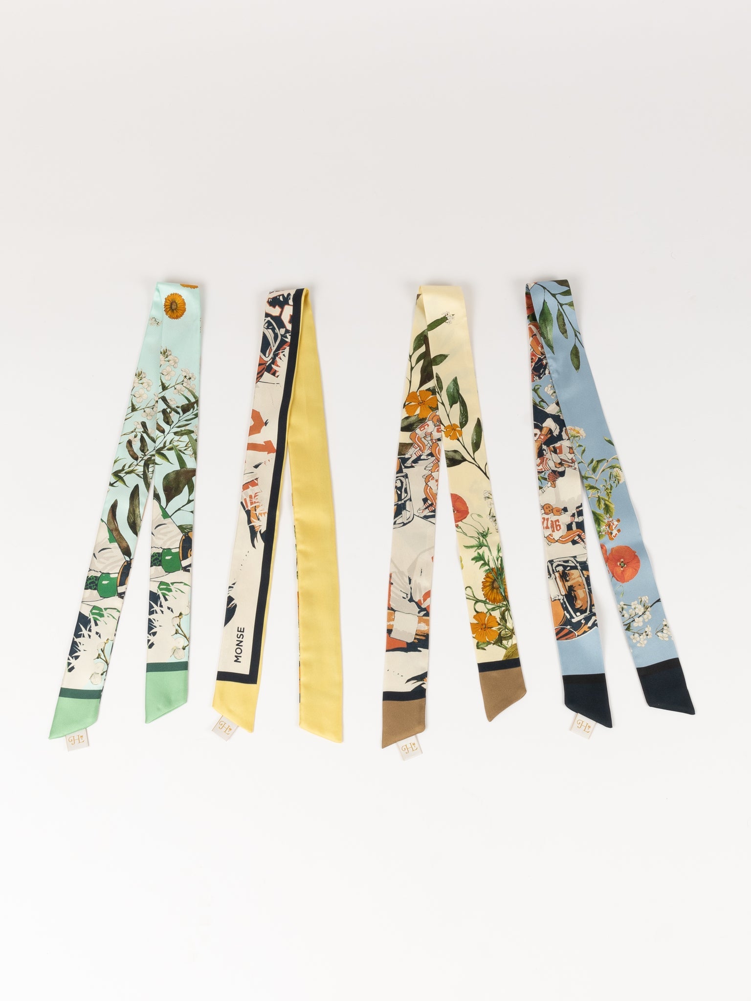 Four J. Logan Home silk accessories laid flat, in mint, butter, cream and pale blue botanical prints